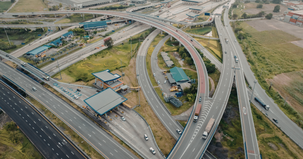 Aerial photo of a highway interchange with multiple ramps and a clear split into two main directions, clean modern look, overcast lighting, lots of negative space, no road signs readable, no text.