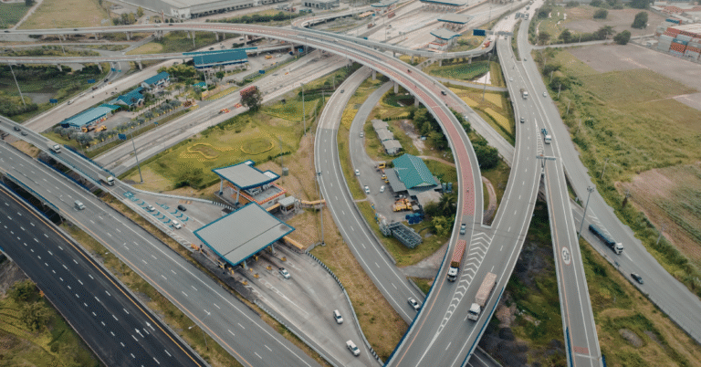 Aerial photo of a highway interchange with multiple ramps and a clear split into two main directions, clean modern look, overcast lighting, lots of negative space, no road signs readable, no text.