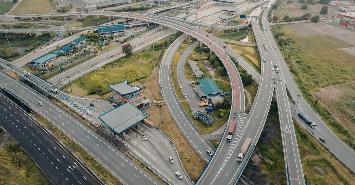 Aerial photo of a highway interchange with multiple ramps and a clear split into two main directions, clean modern look, overcast lighting, lots of negative space, no road signs readable, no text.